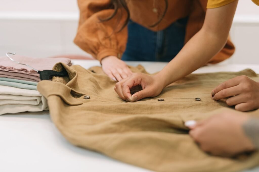 Fashion designers focusing on details of a button-down shirt indoors.